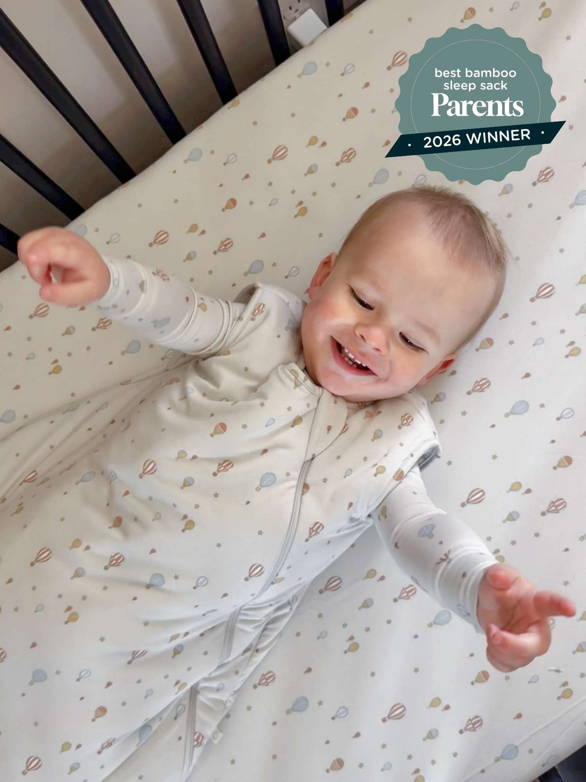Cream 1.0 TOG sleep sack with multicolor planet print, worn by smiling baby