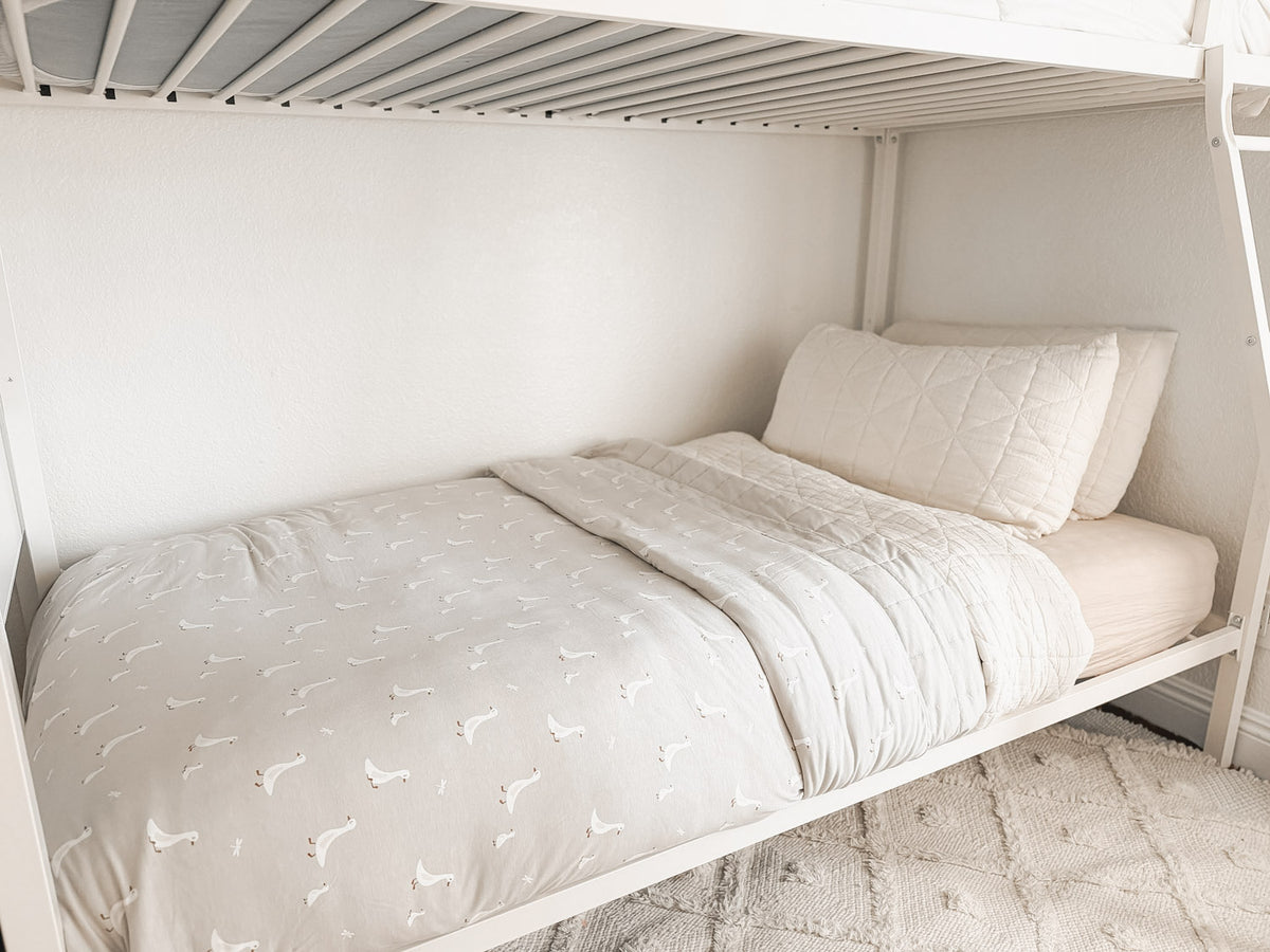 Light gray goose-print twin blanket with matching quilted top, laid on bed.