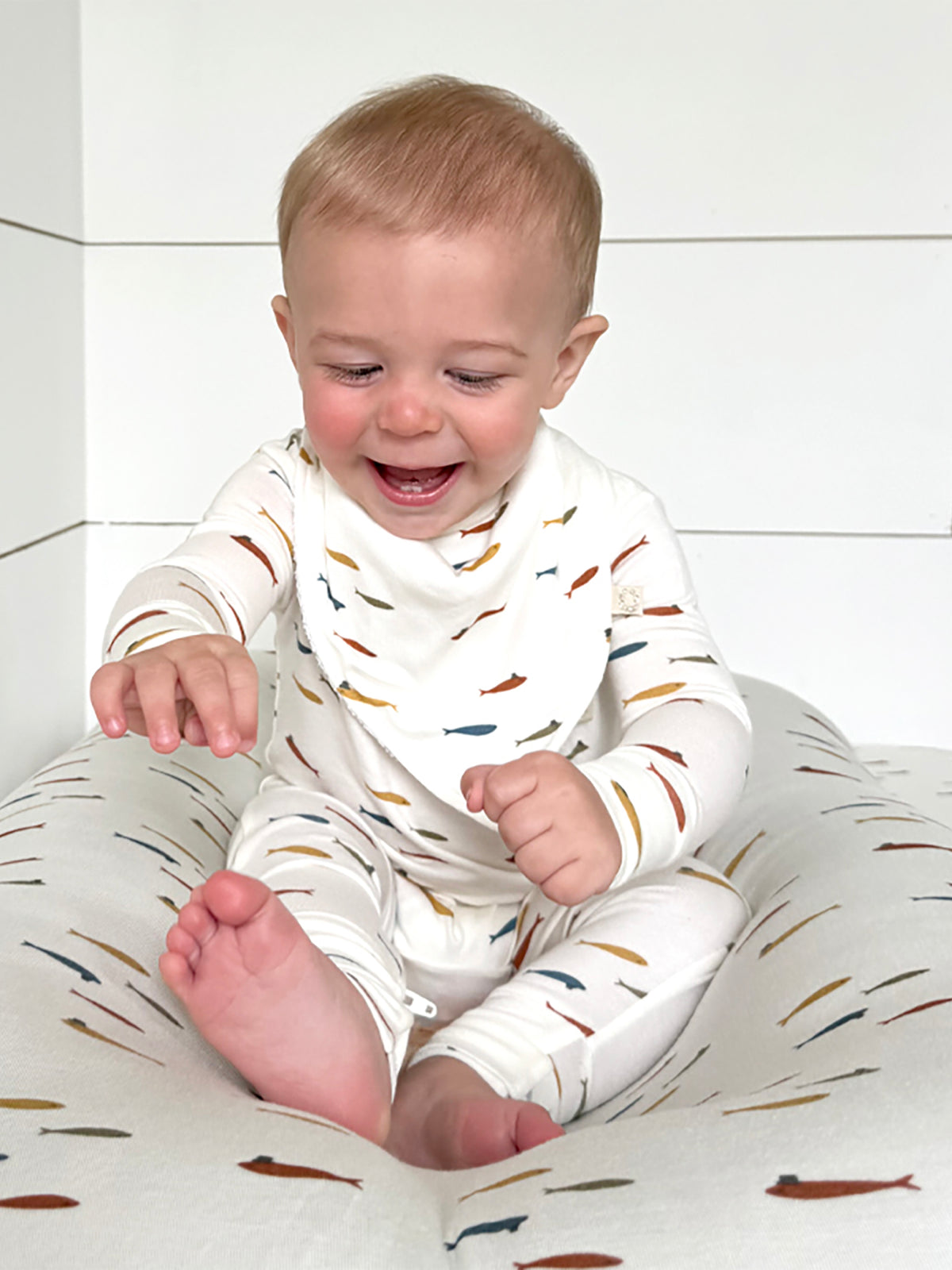 Fish-themed changing pad cover, cream pattern of fish and hats across surface