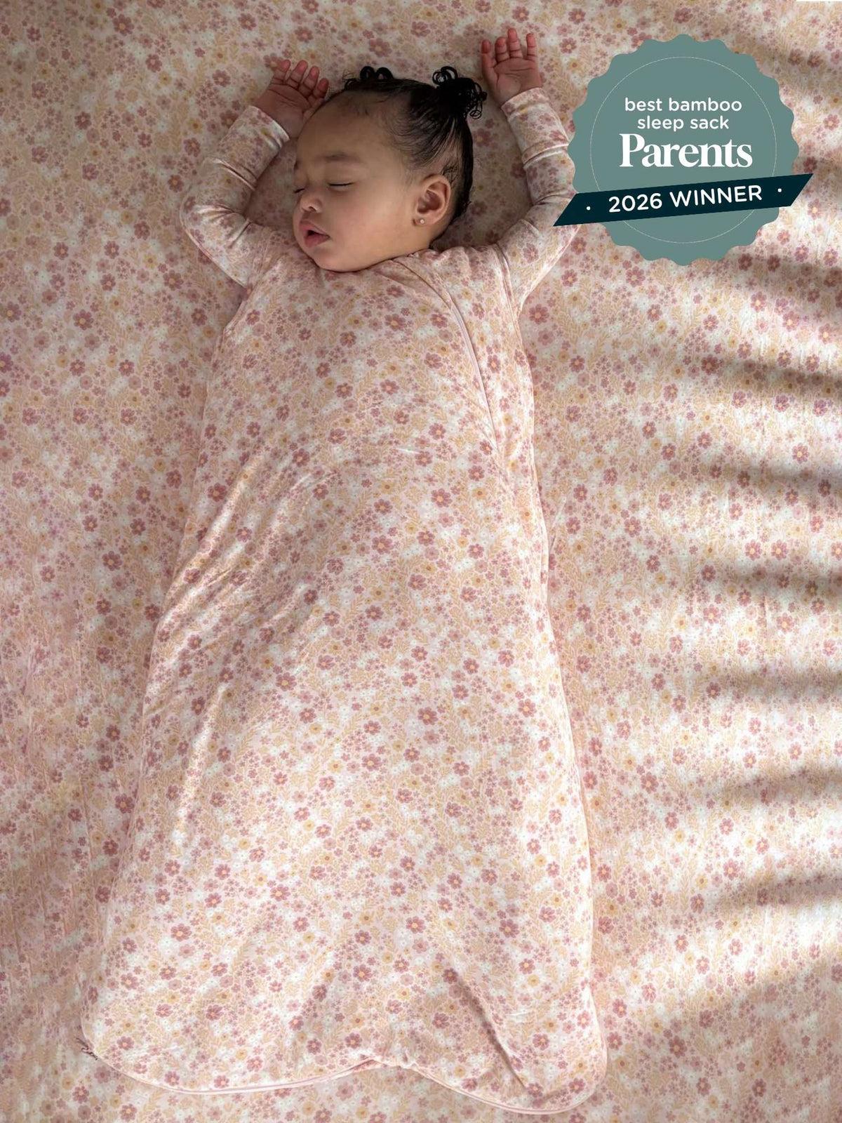 Floral 1.0 TOG sleep sack on bed, long sleeves with zipper front, light pink
