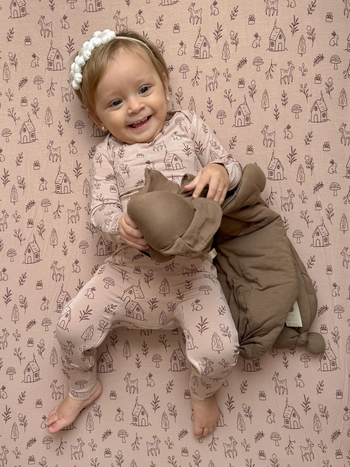 Beige convertible pajamas with farm print and long sleeves, baby wearing white flower headband