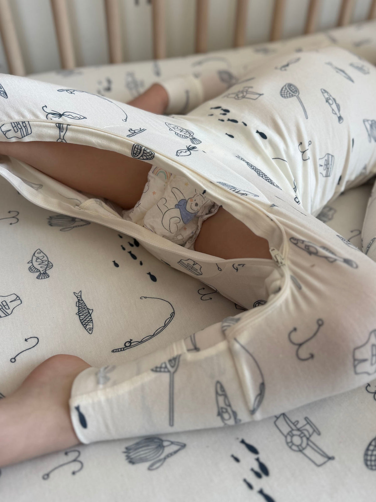 Off-white kids pajama set with fishing-themed print, close-up of legs