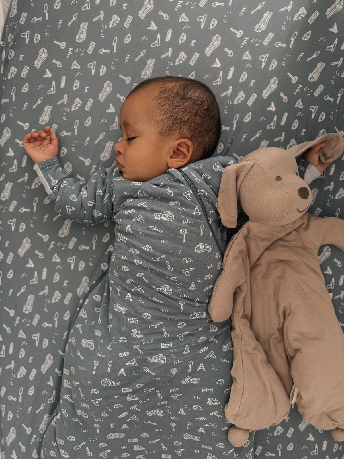 Baby holding a taupe puppy plush lovey with soft ears and stitched face.