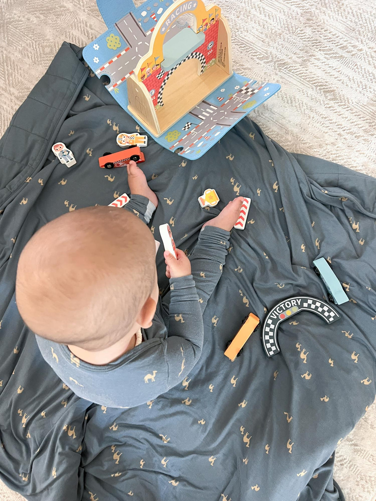Dark blue camel-pattern play blanket with small sewn activity tags