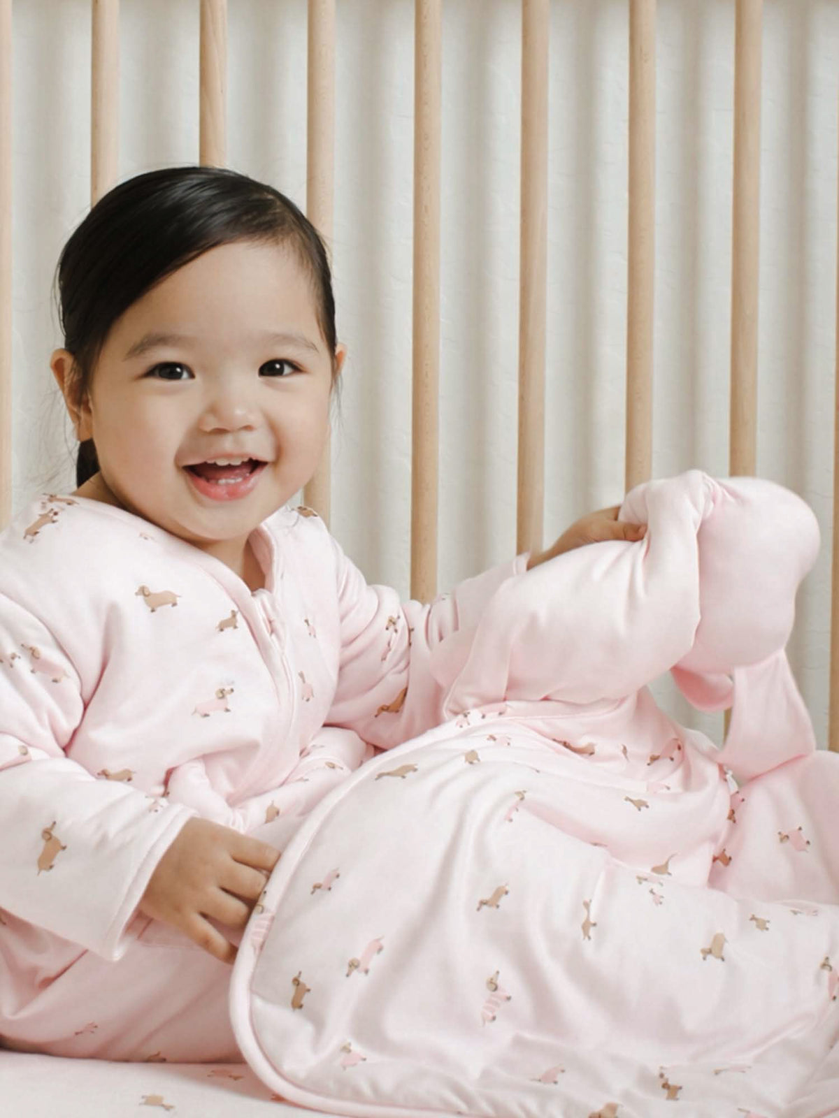 Pink cloud blanket with small dog print, 2.5 TOG, wrapped around a baby