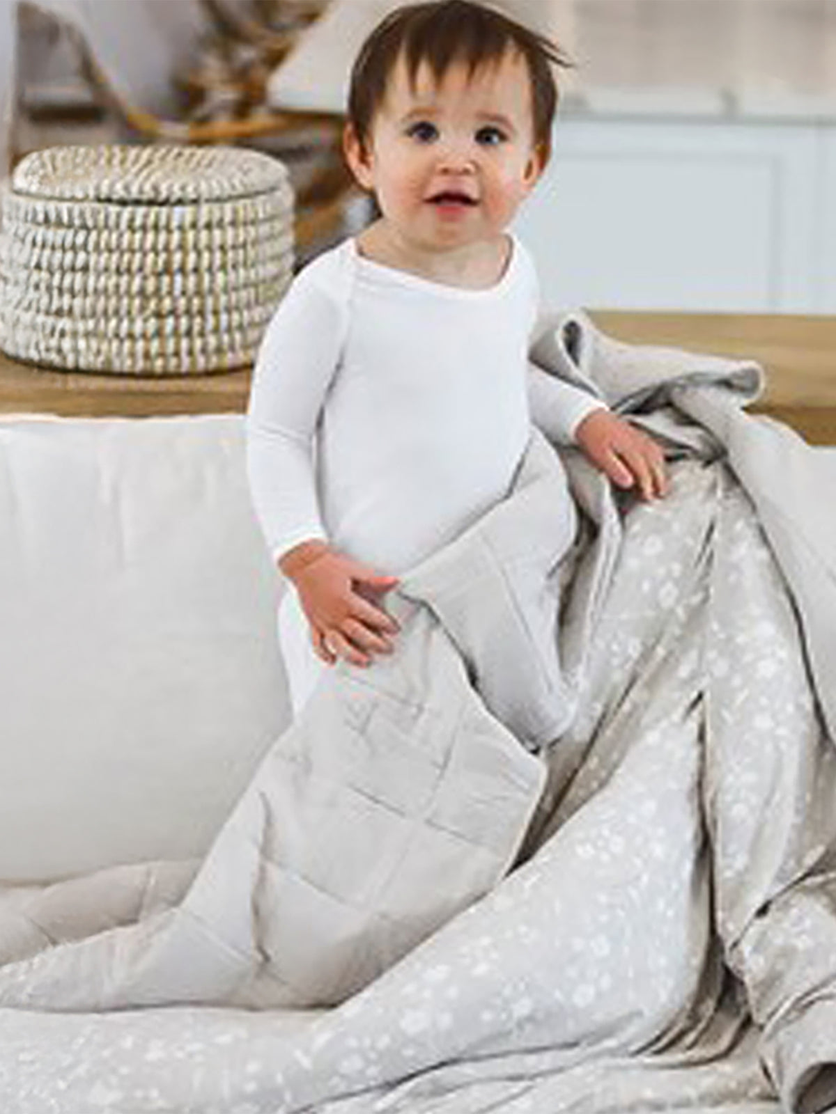 Light beige baby cloud blanket, quilted texture, wrapped around toddler on couch