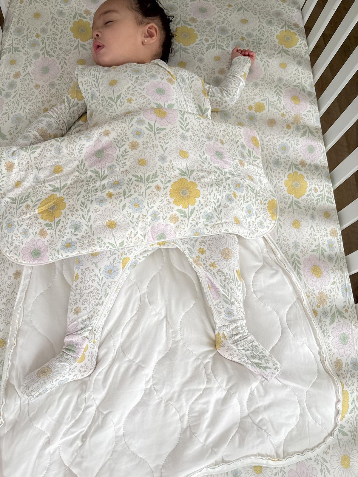 Infant wearing a white floral sleep sack with long sleeves and open foot area