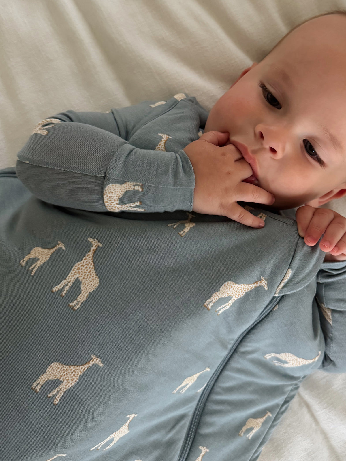 Baby sleep sack close-up, dusty blue with giraffe print, long sleeves, front zip