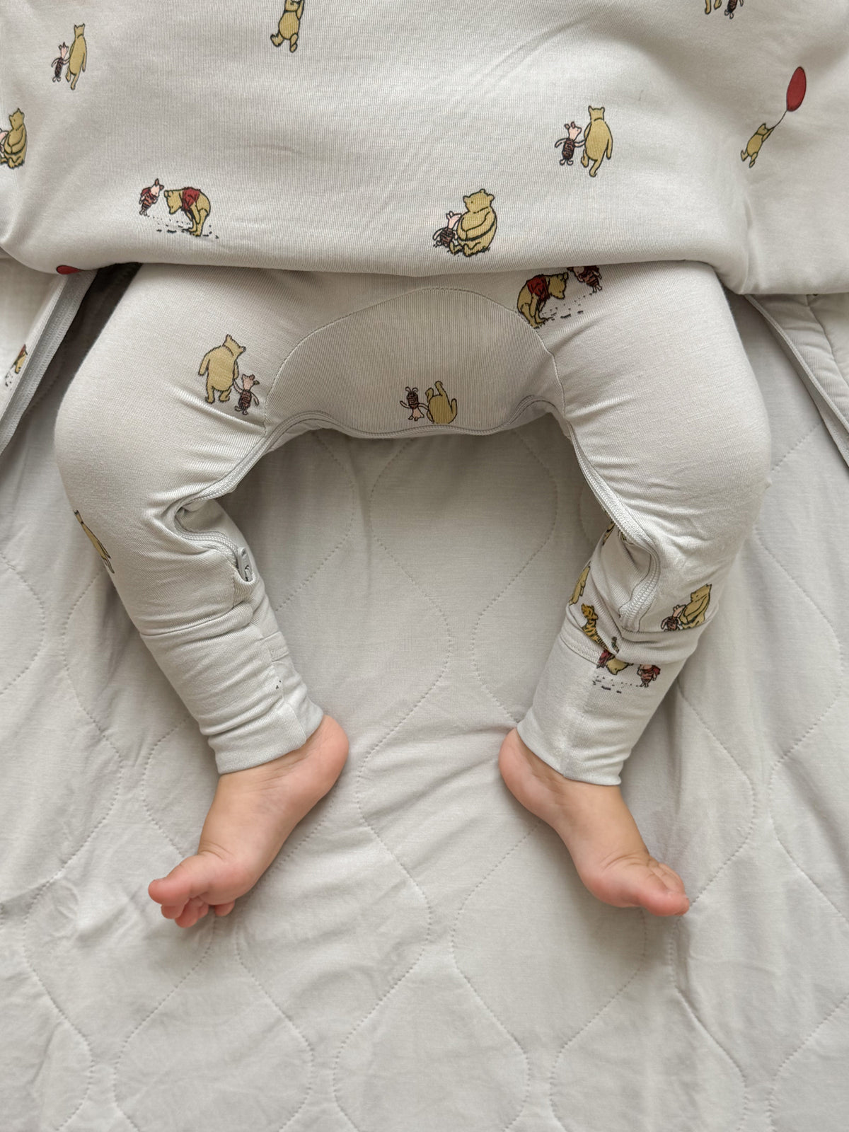 White baby sleep sack with Pooh character print and leg openings for feet