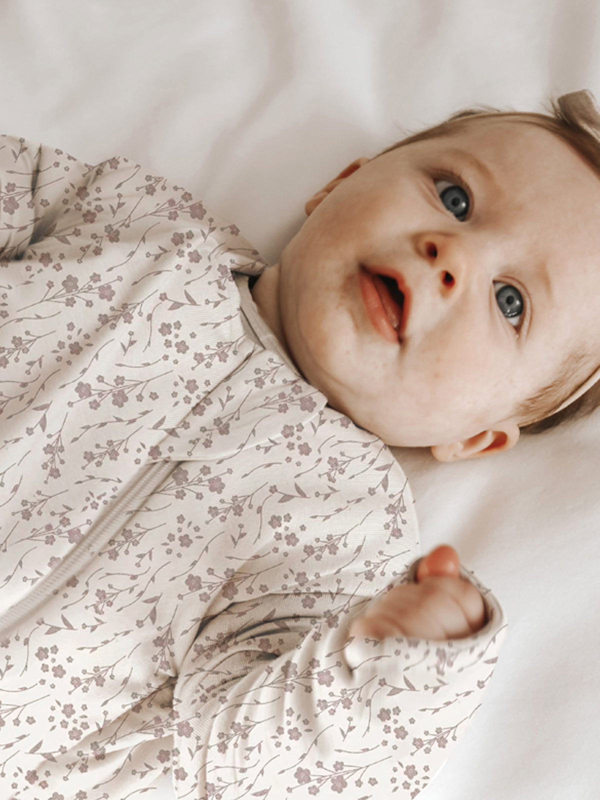 Newborn in cream floral long-sleeve sleep sack with zip front, soft gathered neck
