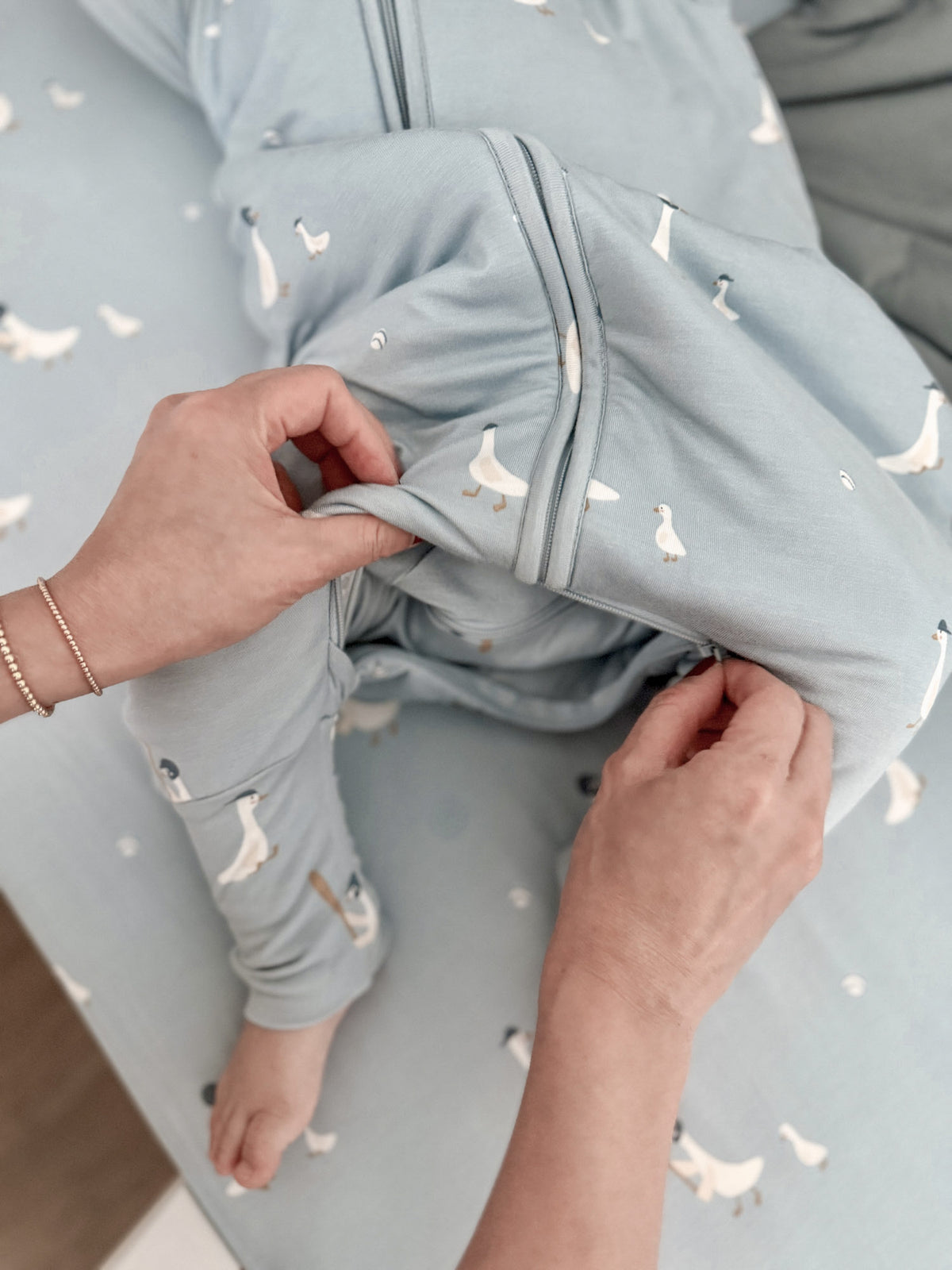 Footie sleep sack close-up in light blue with swan print and zipper front