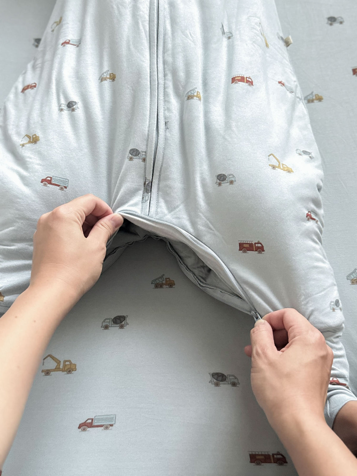 Footie sleep sack unzips to reveal interior lining, light blue vehicle print