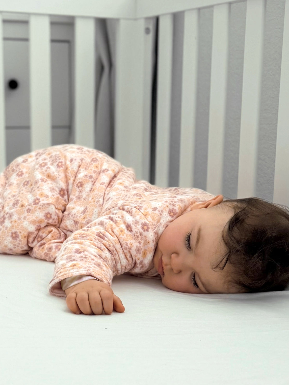 Long-sleeve footed sleep sack with pastel floral print, zipper front, side view