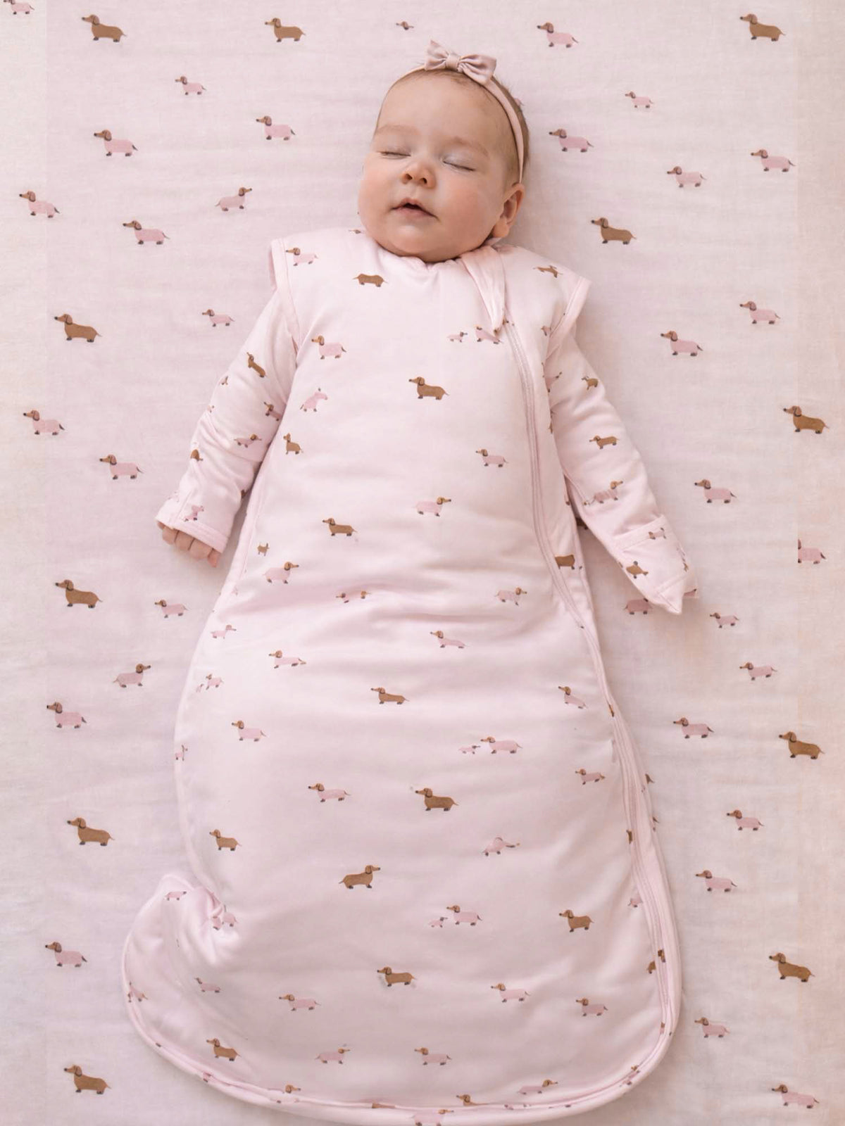 Light pink 2.5 TOG swaddle sleep sack with dog print and full-length zip front