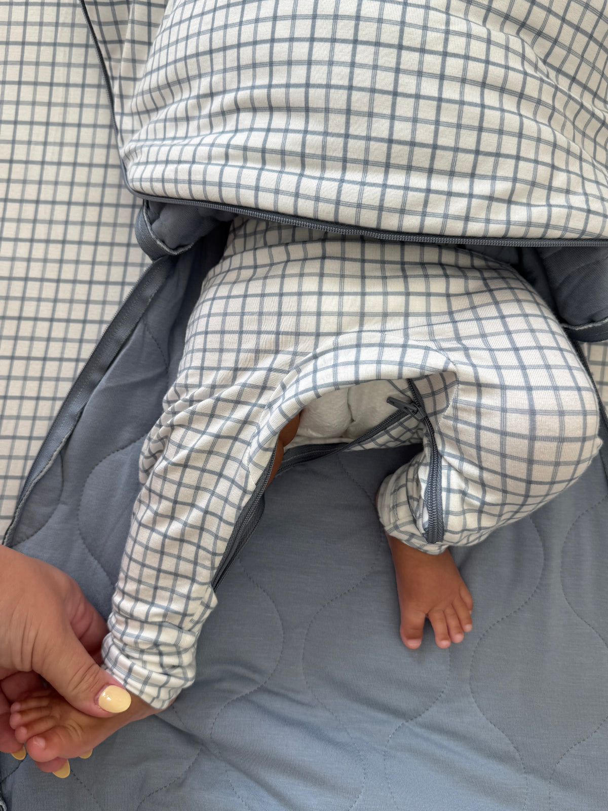 Checkered transitional swaddle sleep sack with gray cuffs and zippered opening
