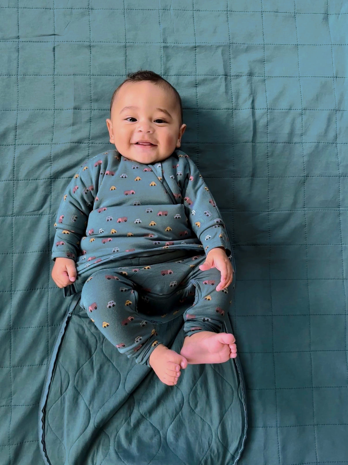 Teal long-sleeve swaddle sack with multicolor vehicle print, open leg design