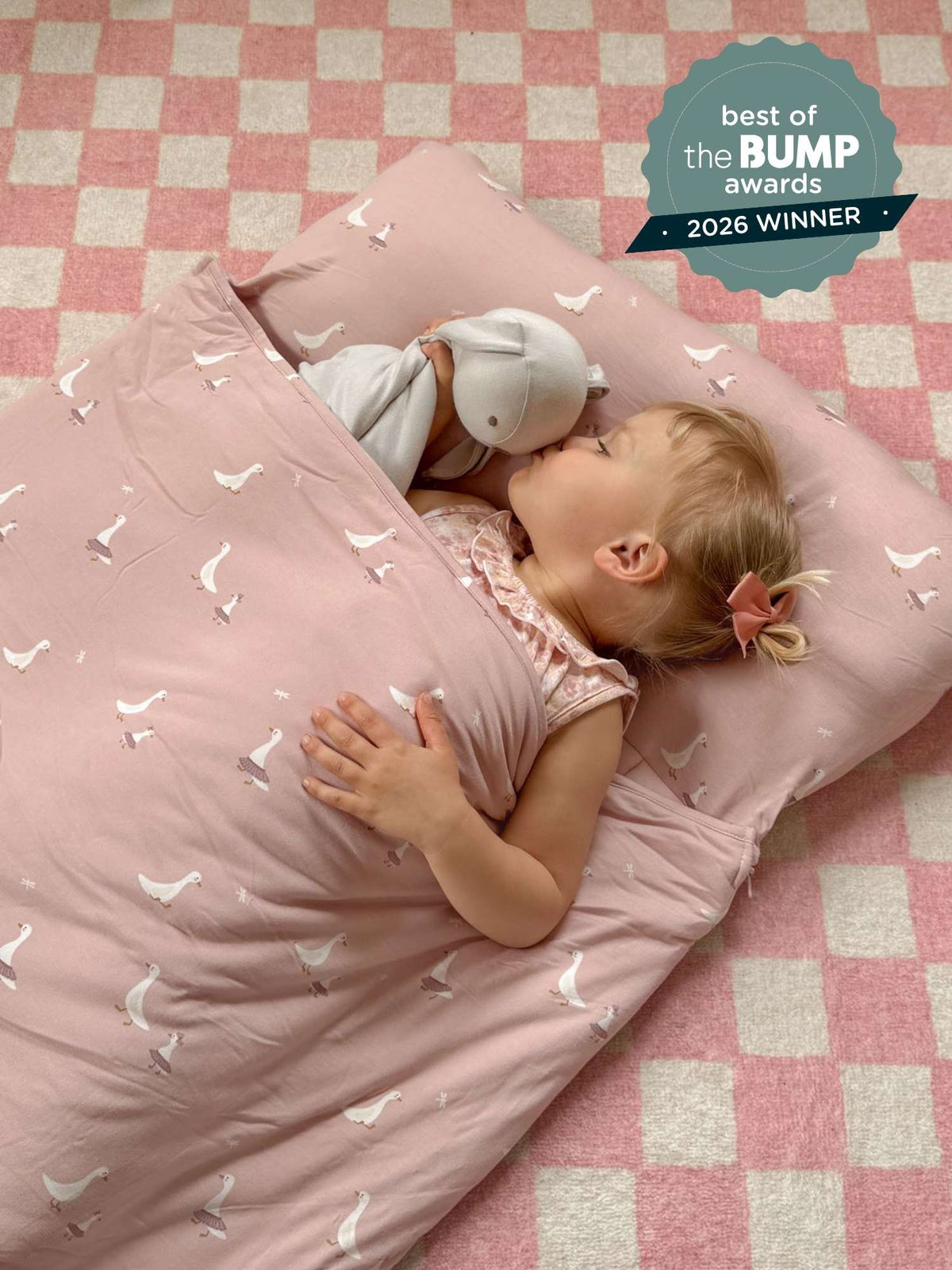 Light pink nap mat with white goose pattern, baby lying on the mat