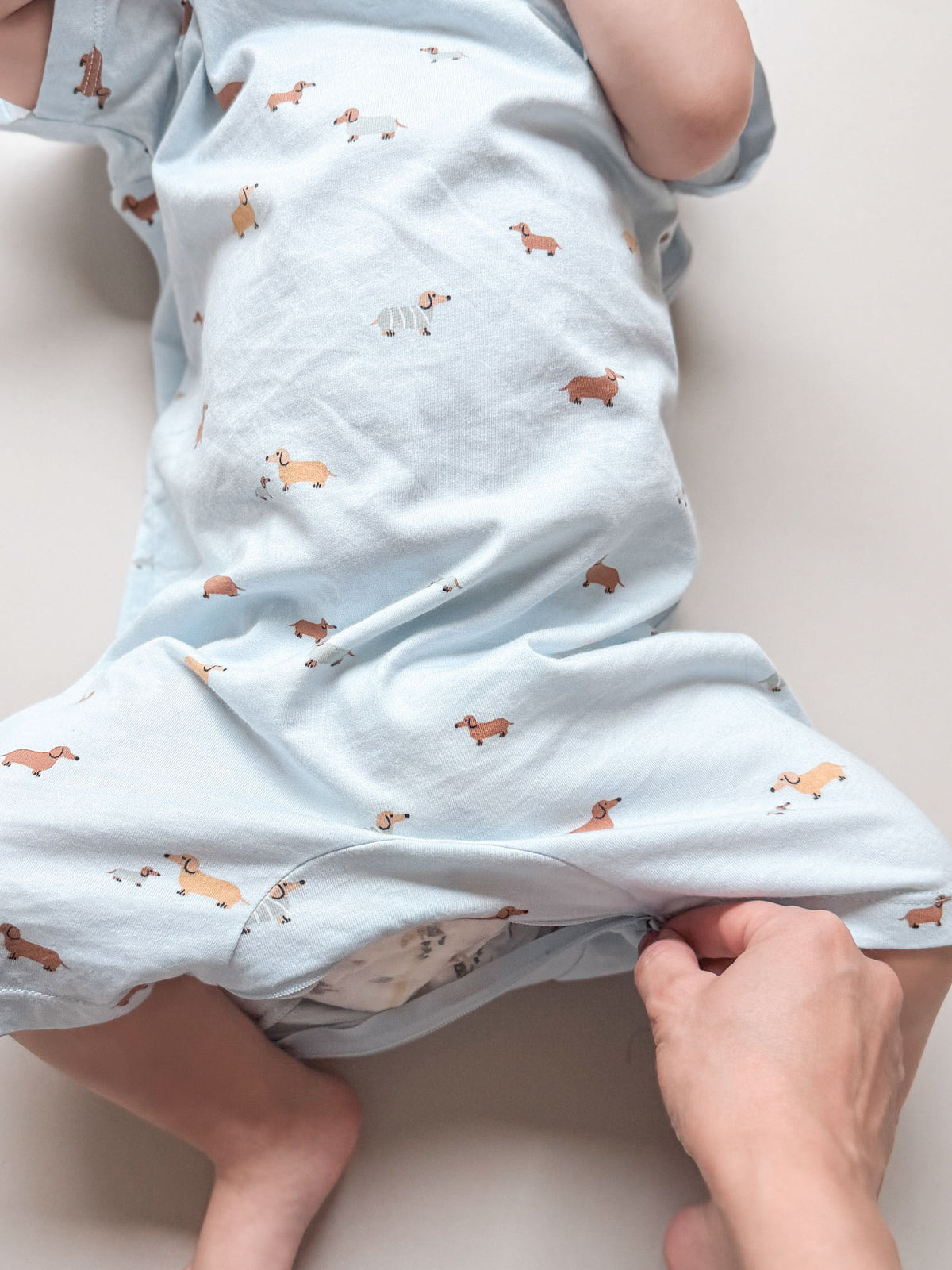 Woof cotton shortie romper, light blue fabric with scattered dog print; arm and leg