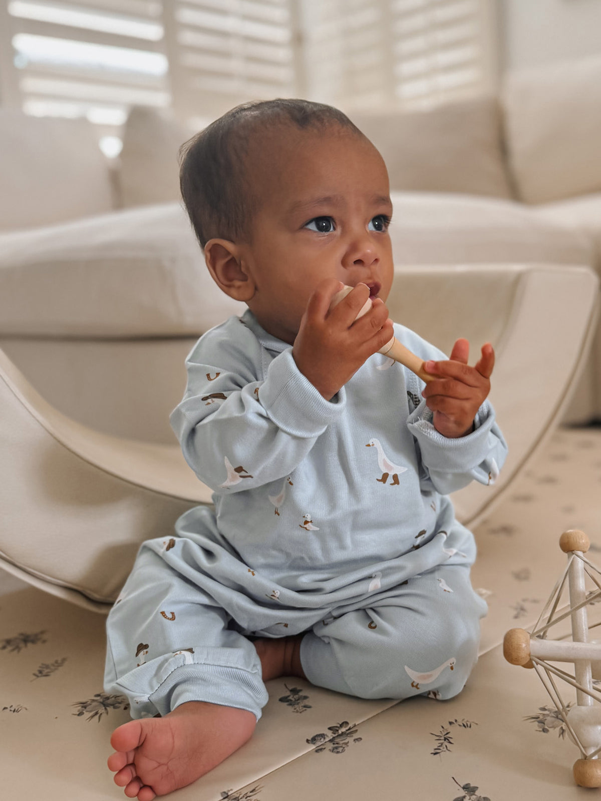 Light blue fleece jumpsuit with long sleeves and animal print, baby sitting