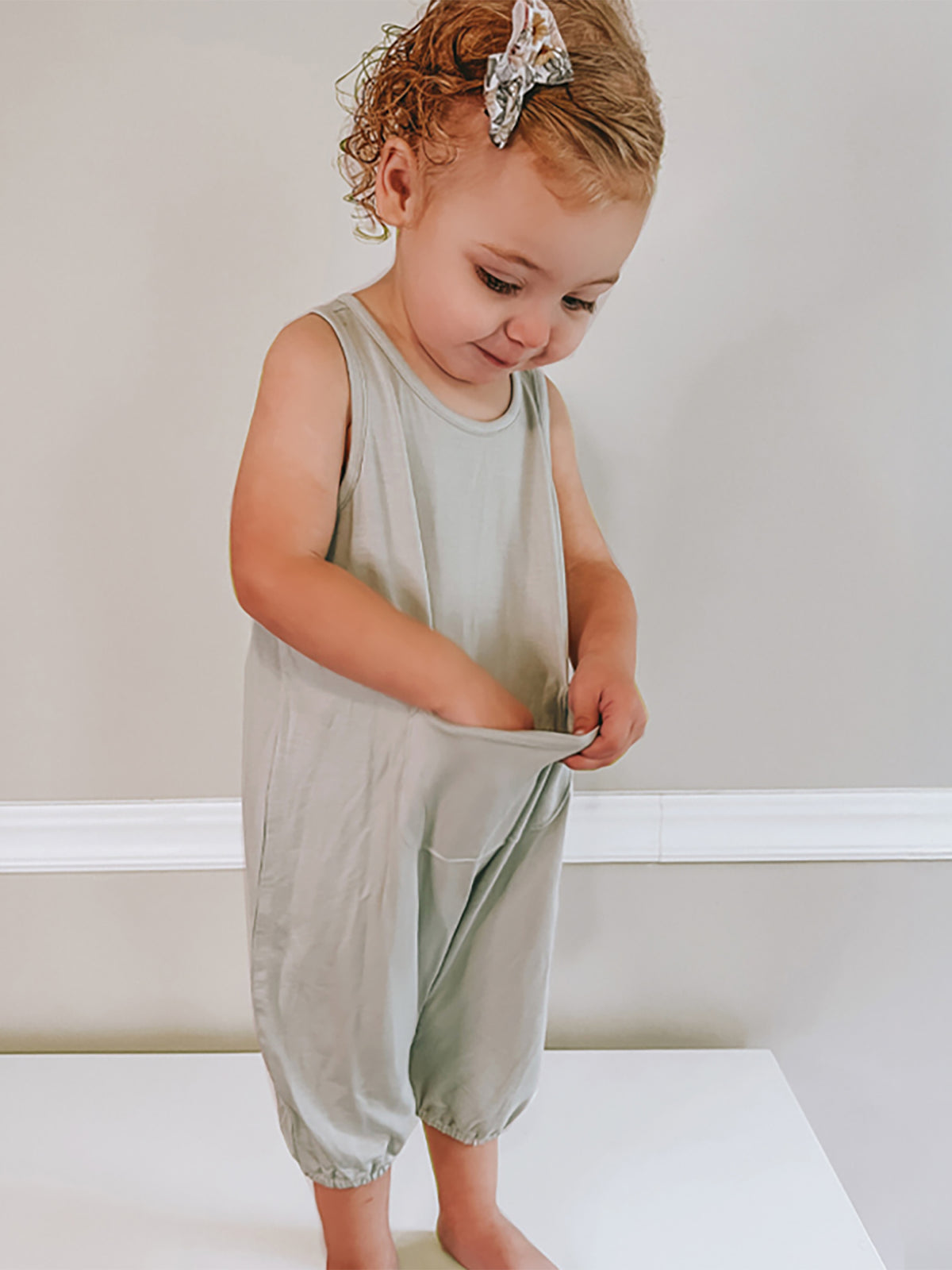 Sage green sleeveless short romper with loose legs and wide leg openings