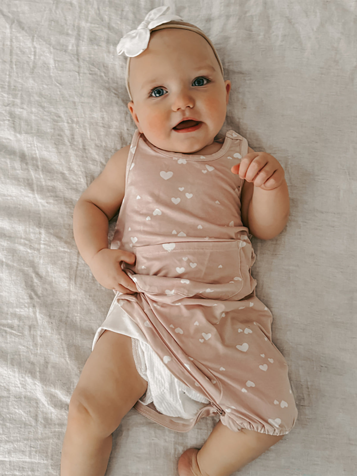 Light pink sleeveless romper with white heart print, soft gathered waist and legs