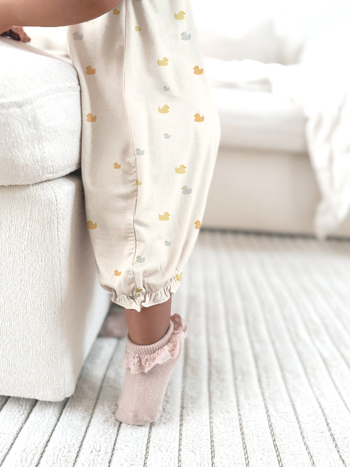 Cream duck-print romper with ruffled collar and gathered cuffs, worn with socks