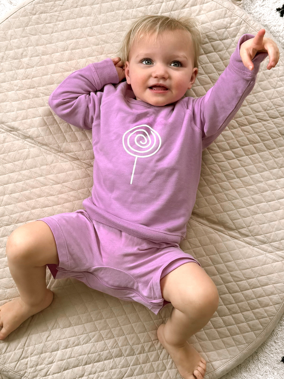 Lilac long-sleeve crewneck sweatshirt with white lollipop swirl logo on chest