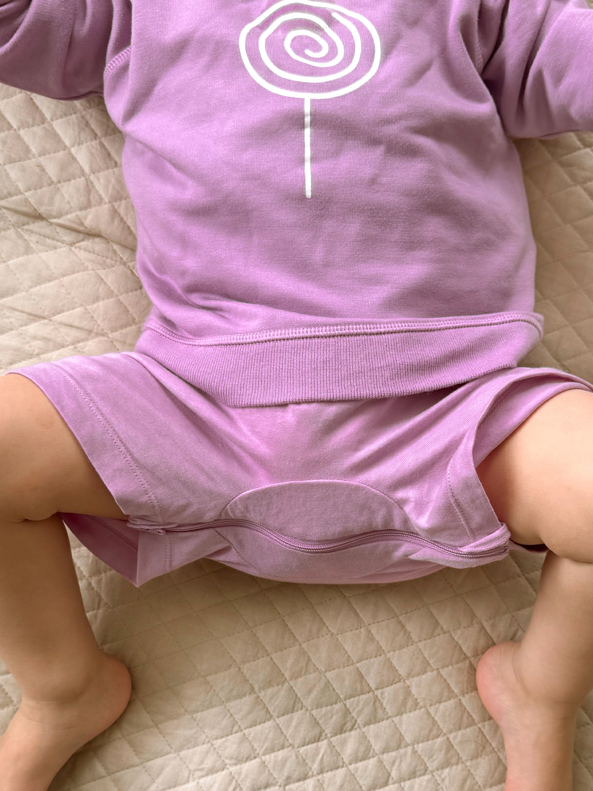 Lavender crewneck sweatshirt with long sleeves and white lollipop swirl graphic