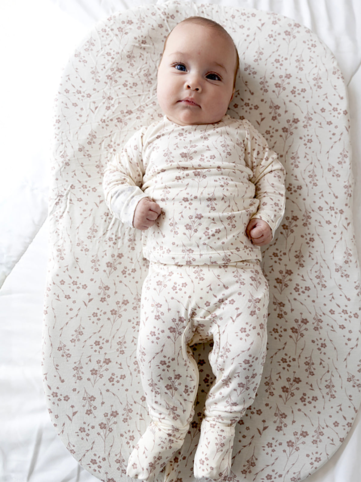 Cream floral two-piece footie set, long sleeves and footed legs; baby centered