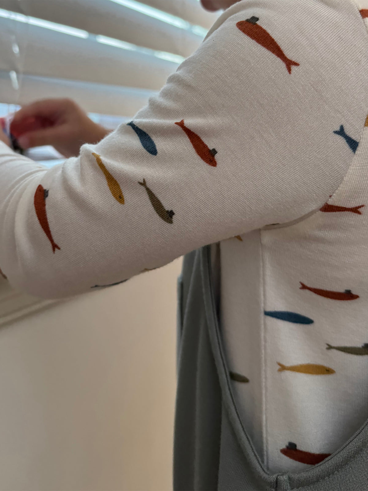 Fish-pattern sleeve detail on light gray fleece overall set, close-up