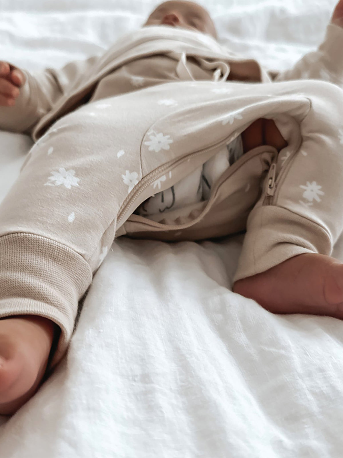 Light blush fleece pullover with white flower print and zip-front leg opening