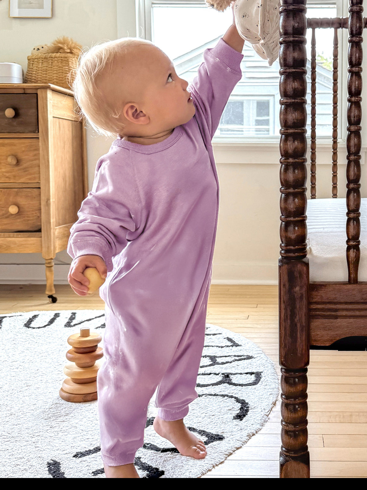 Lilac long-sleeve cotton jumpsuit on toddler standing, relaxed one-piece with cuffed sleeves