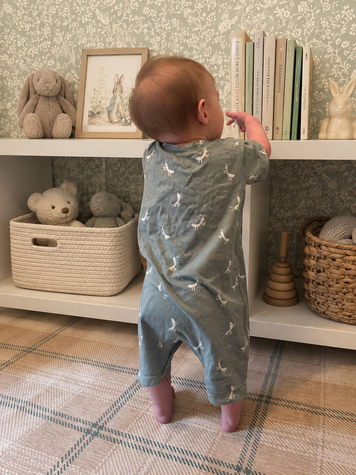 Sage green cotton short romper with white animal prints, back view with short legs
