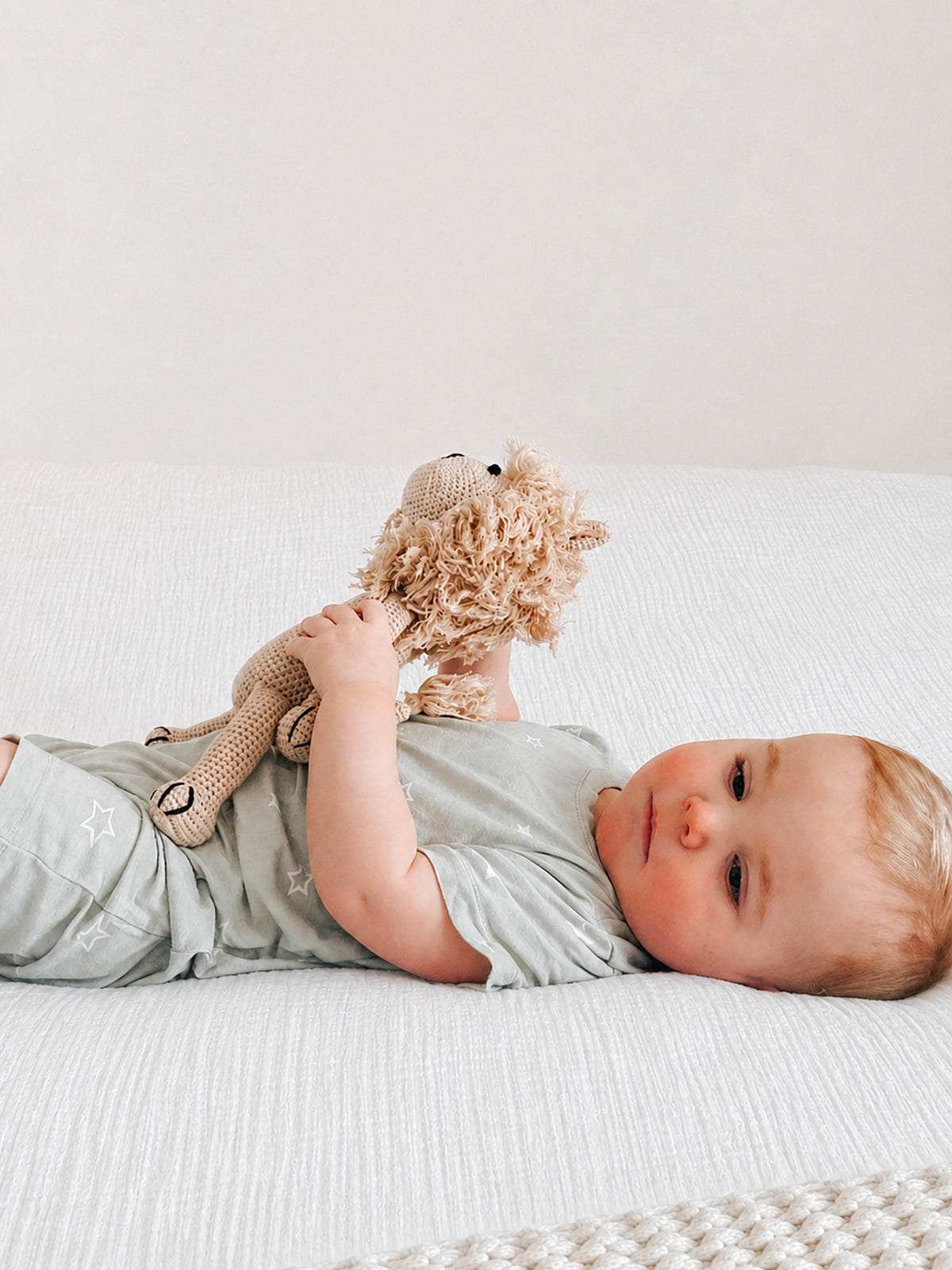 Sage gray shortie romper with white stars, short sleeves, baby lying on back