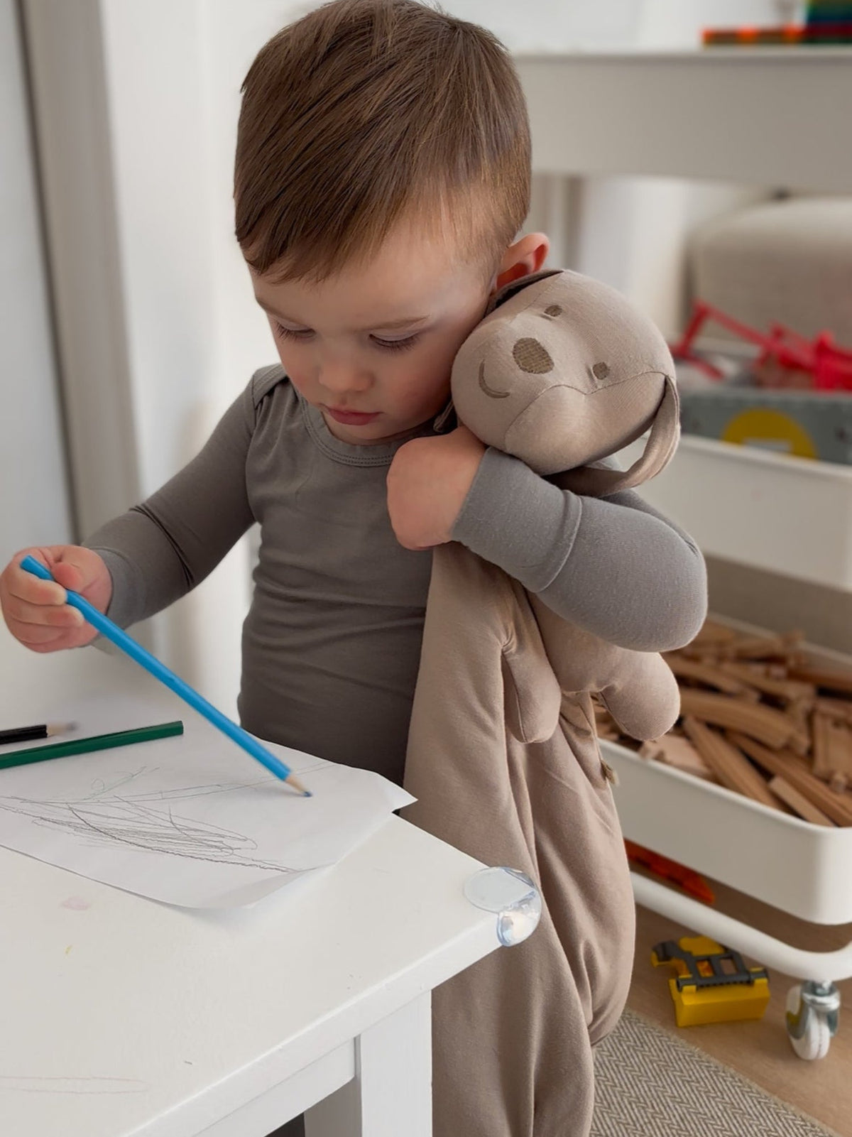Taupe puppy plush lovey in a toddler’s arms next to a craft table.