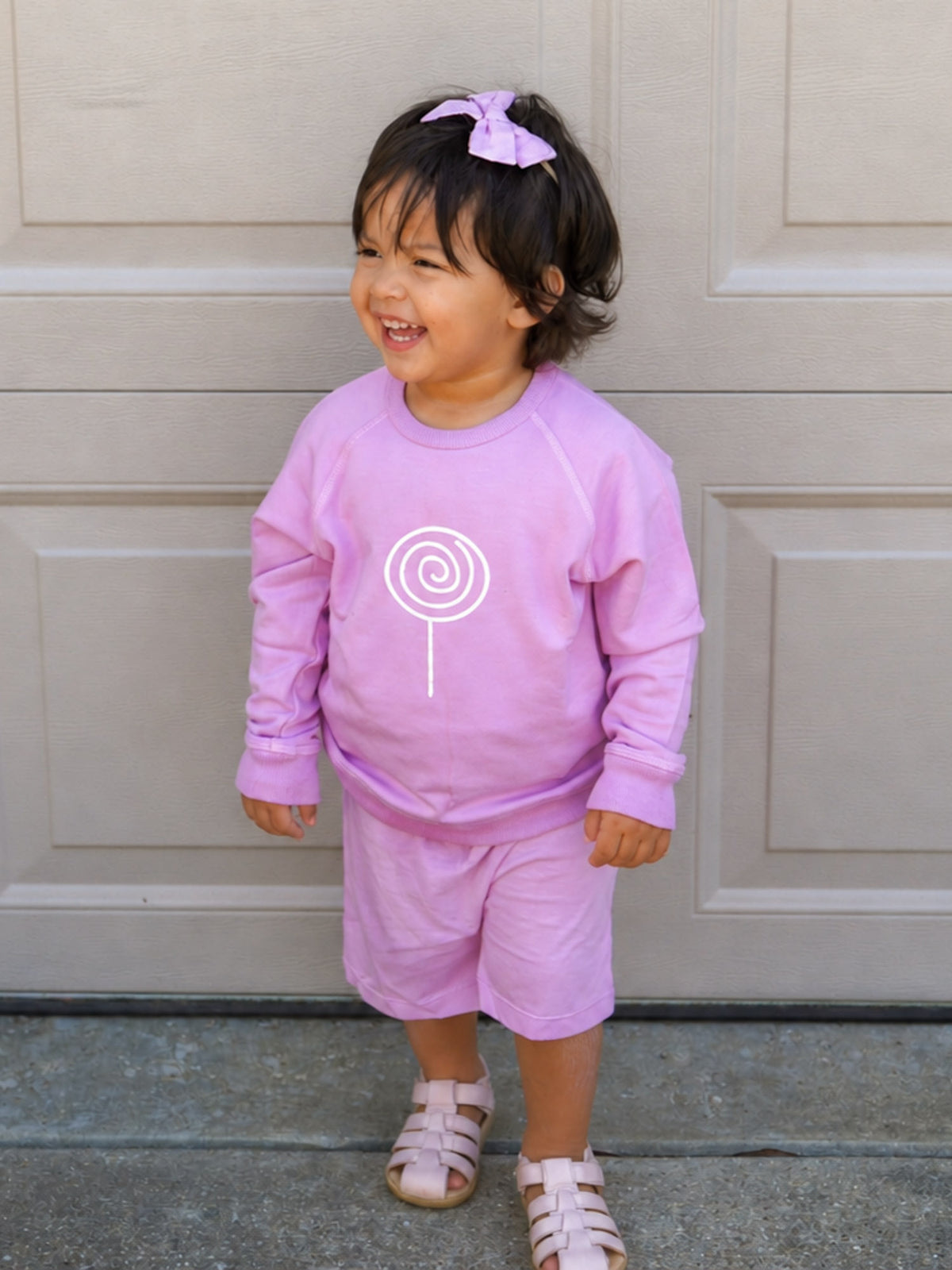 Lilac crewneck sweatshirt with white lollipop swirl graphic, full front