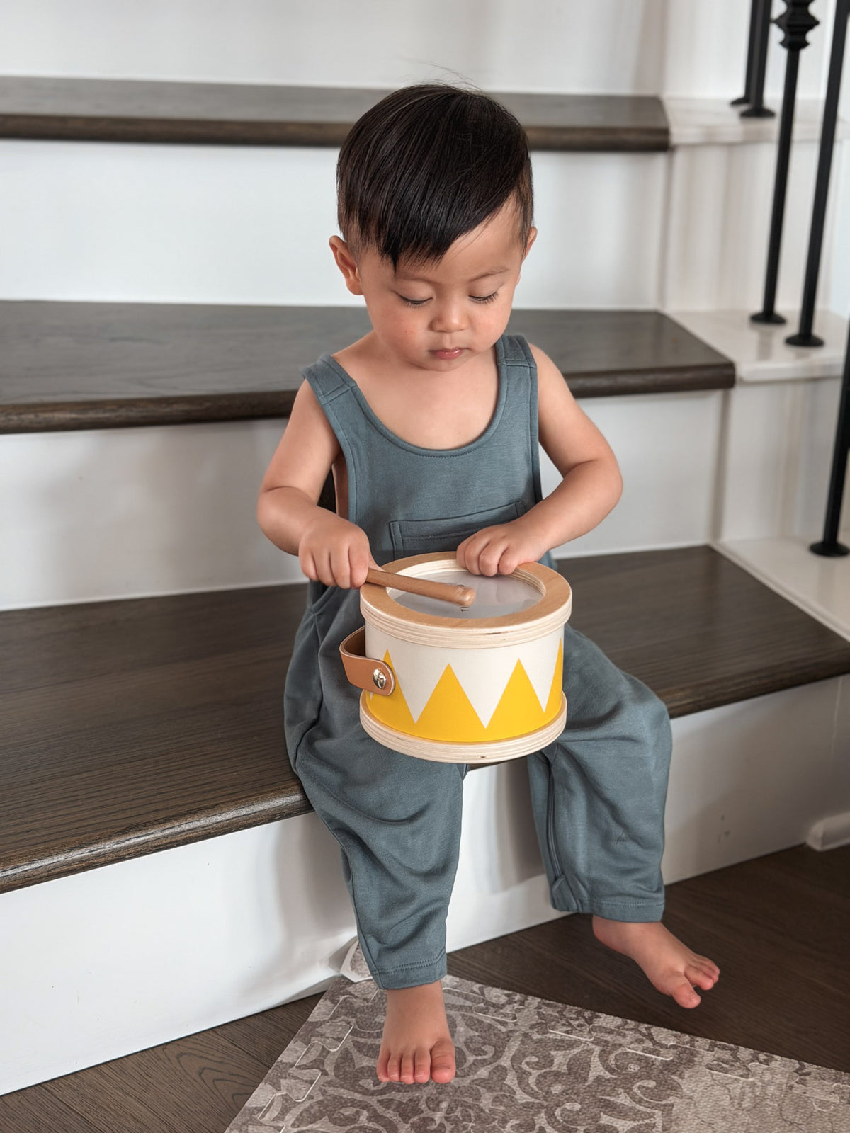 Teal fleece baby overalls on a standing toddler, front pocket detail