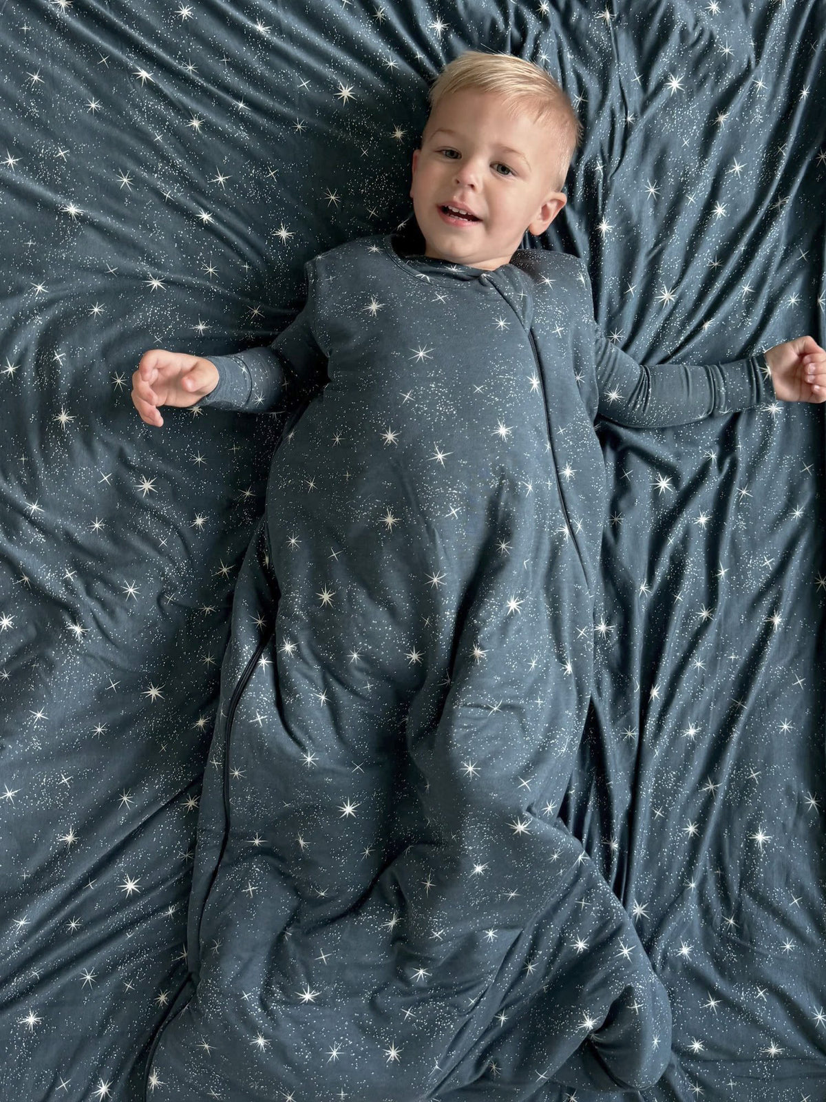 Dark blue star-print sleep sack, long sleeves visible with arms out