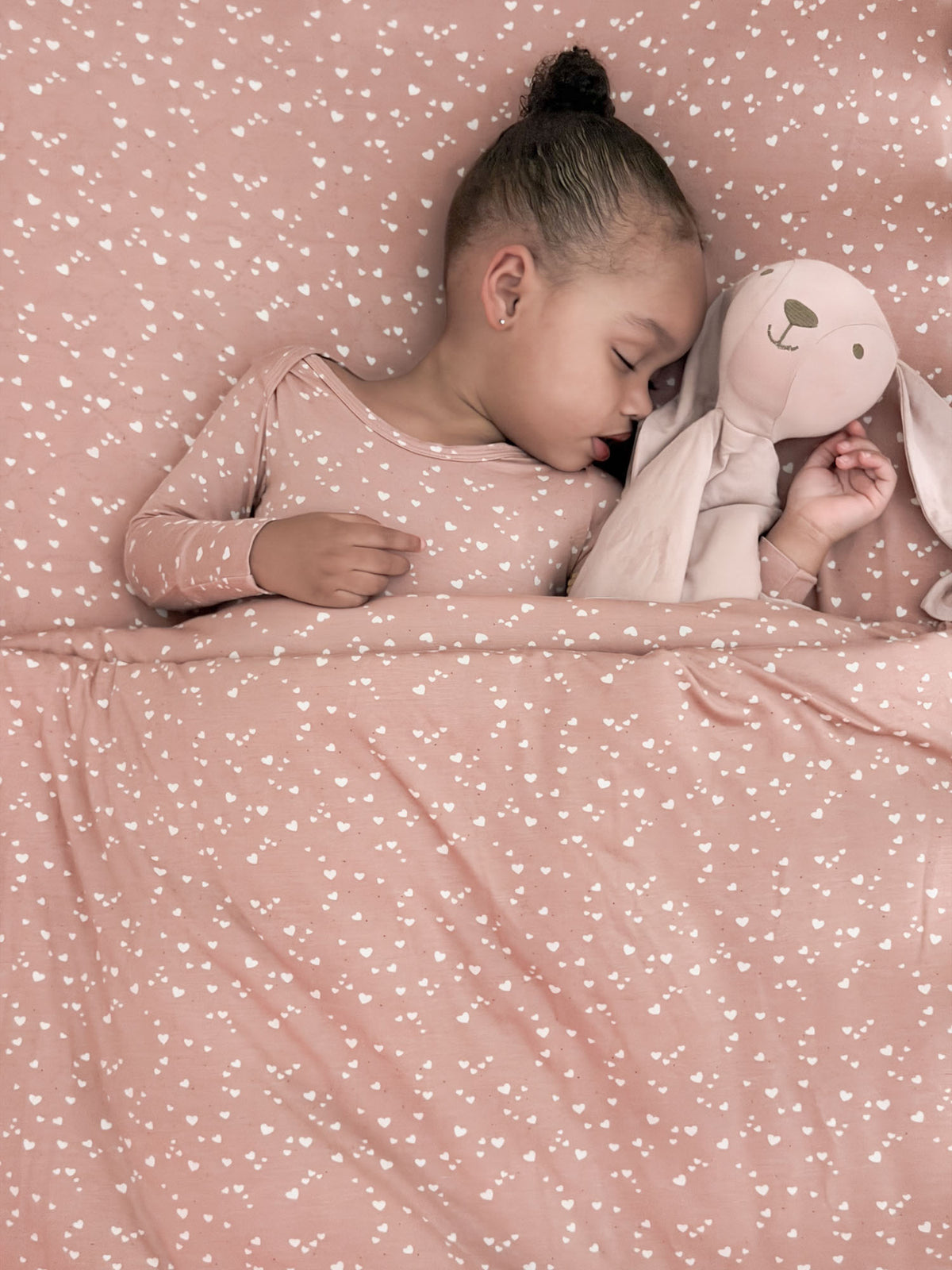 Twin cloud blanket with all-over heart pattern, dusty rose, neatly spread on bed