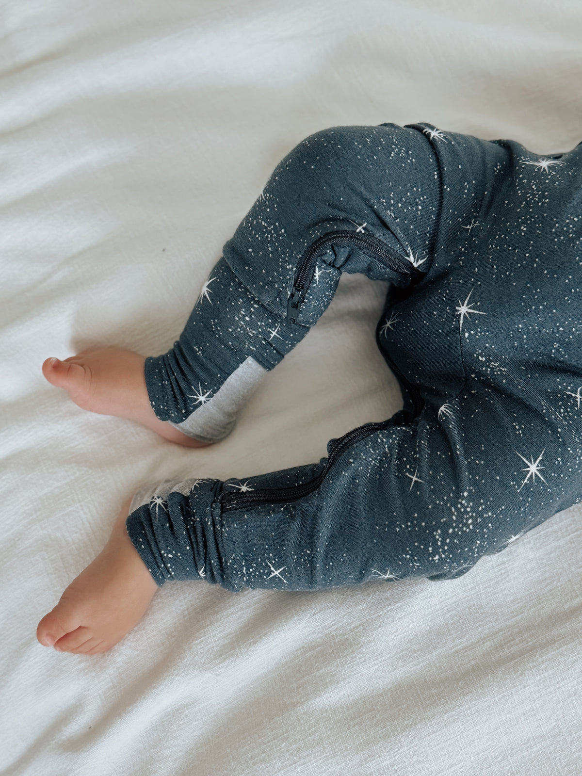 Infant convertible pajama in dark navy with white star print, lying flat showing full length