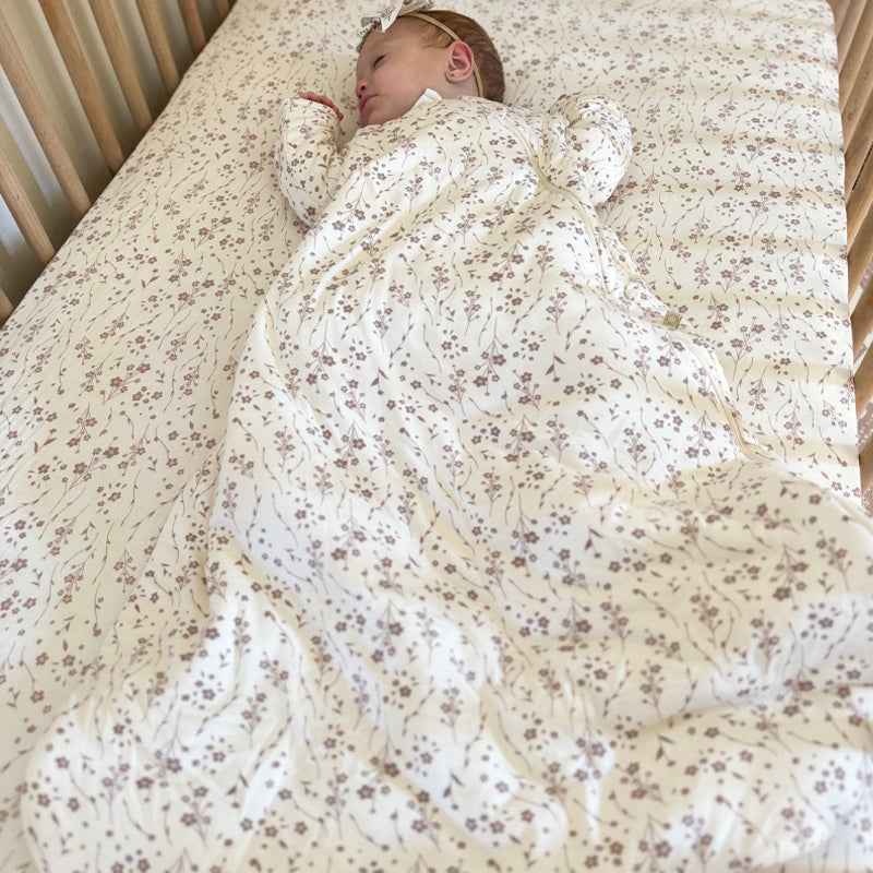 Cream floral long-sleeve sleep sack with gathered back, baby resting on bed