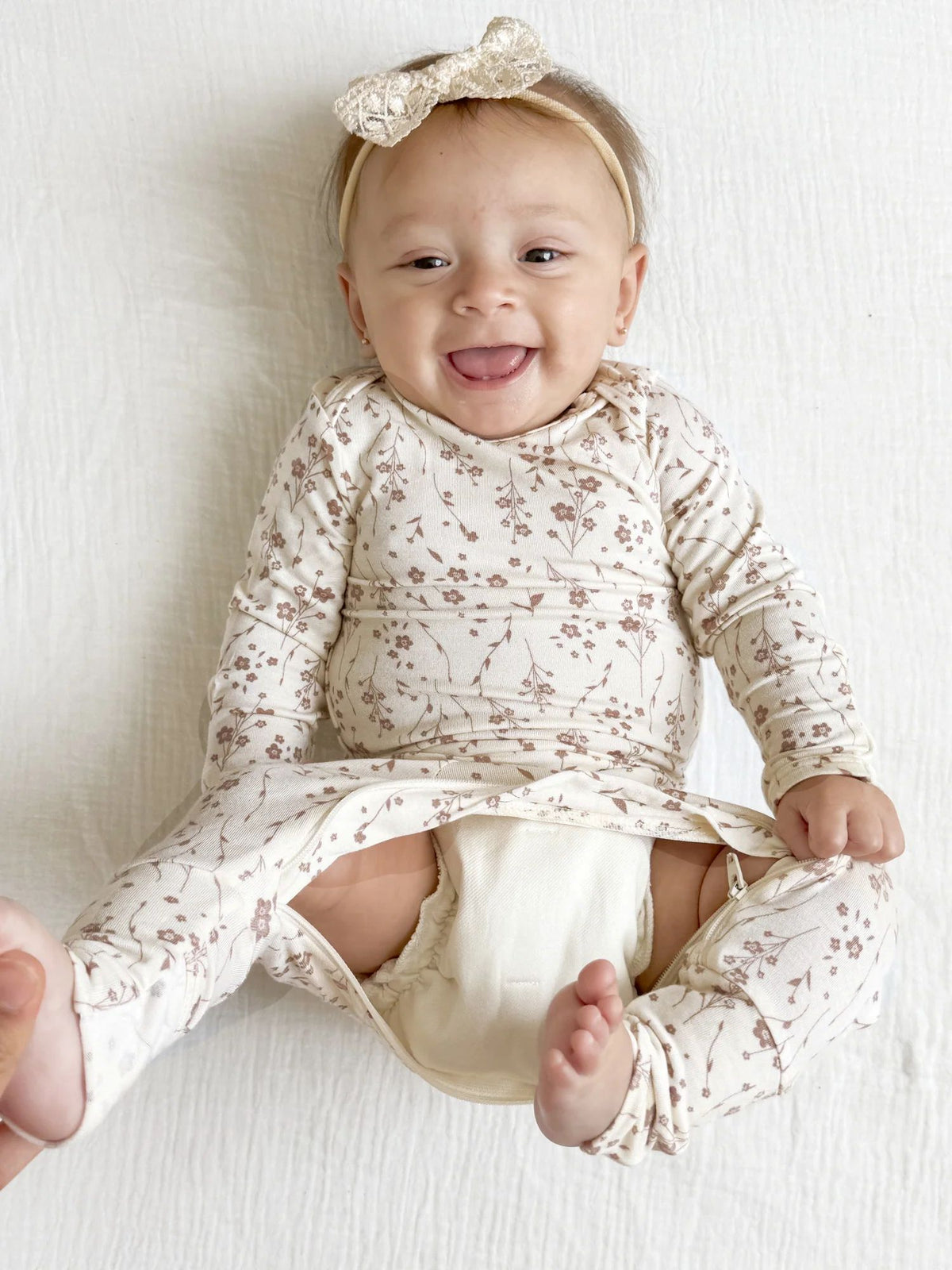 Convertible baby pajama with beige floral print, long sleeves and open crotch area