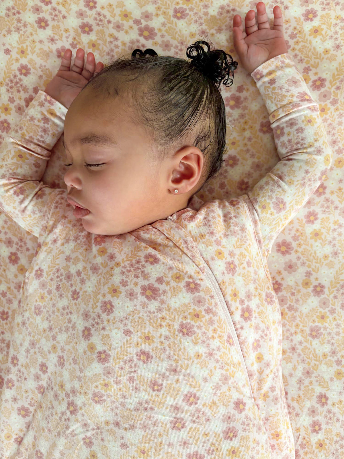 Floral sleep sack with long sleeves and front zipper, baby lying with arms up