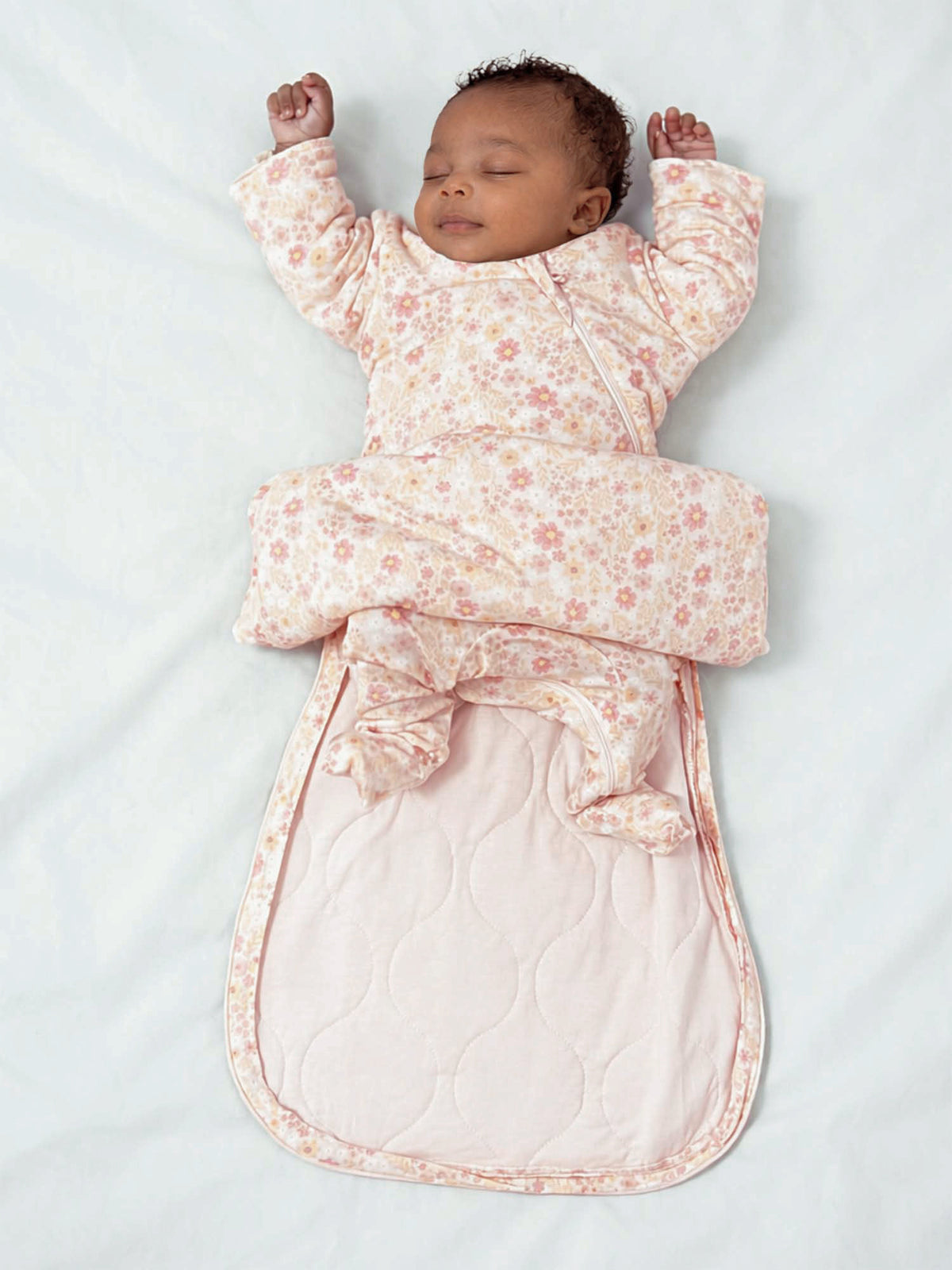Floral long-sleeve swaddle sleep sack with arms-out wings, soft pink and beige.