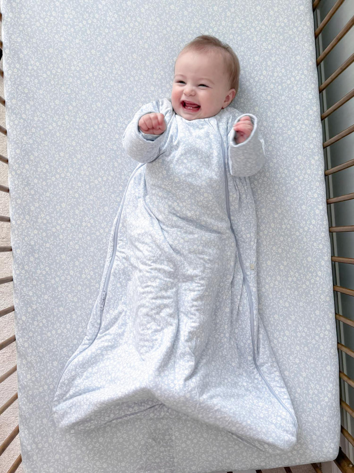 Light gray patterned long-sleeve sleep sack with front zipper and enclosed feet.