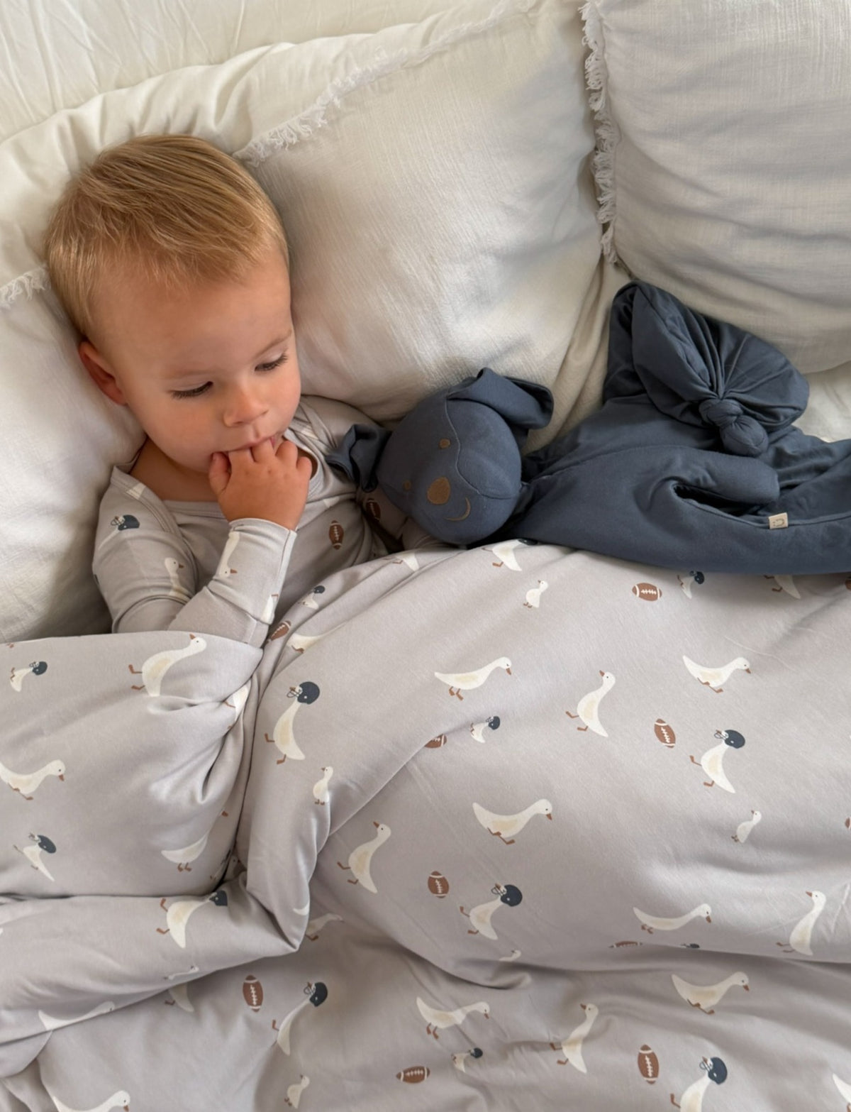 Light gray baby blanket with repeating goose print and navy accents, folded