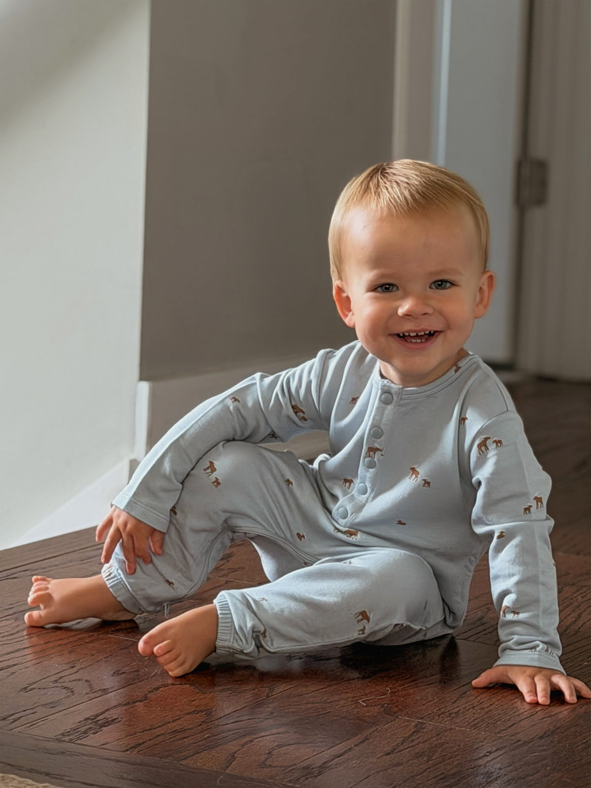 Light blue baby henley jumpsuit with long sleeves, allover moose print, button placket