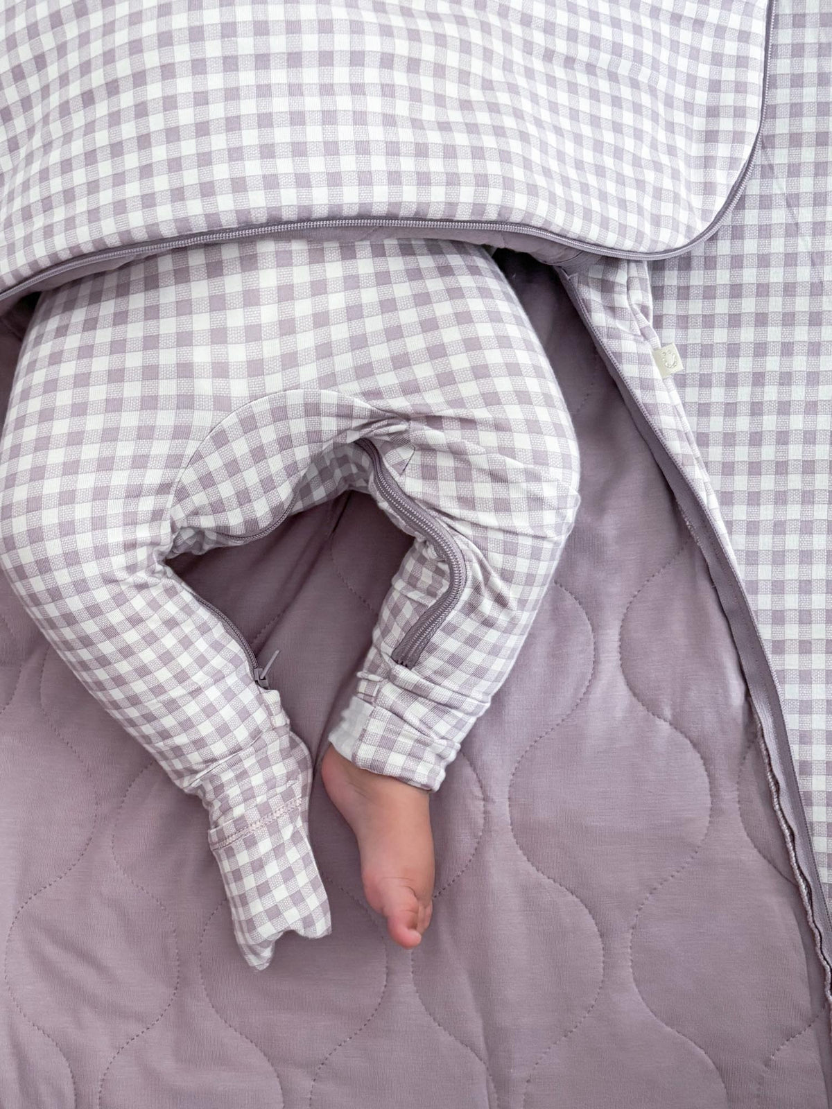 Checkered long-sleeve sleep sack with arm opening and draped leg panel, gray lining.