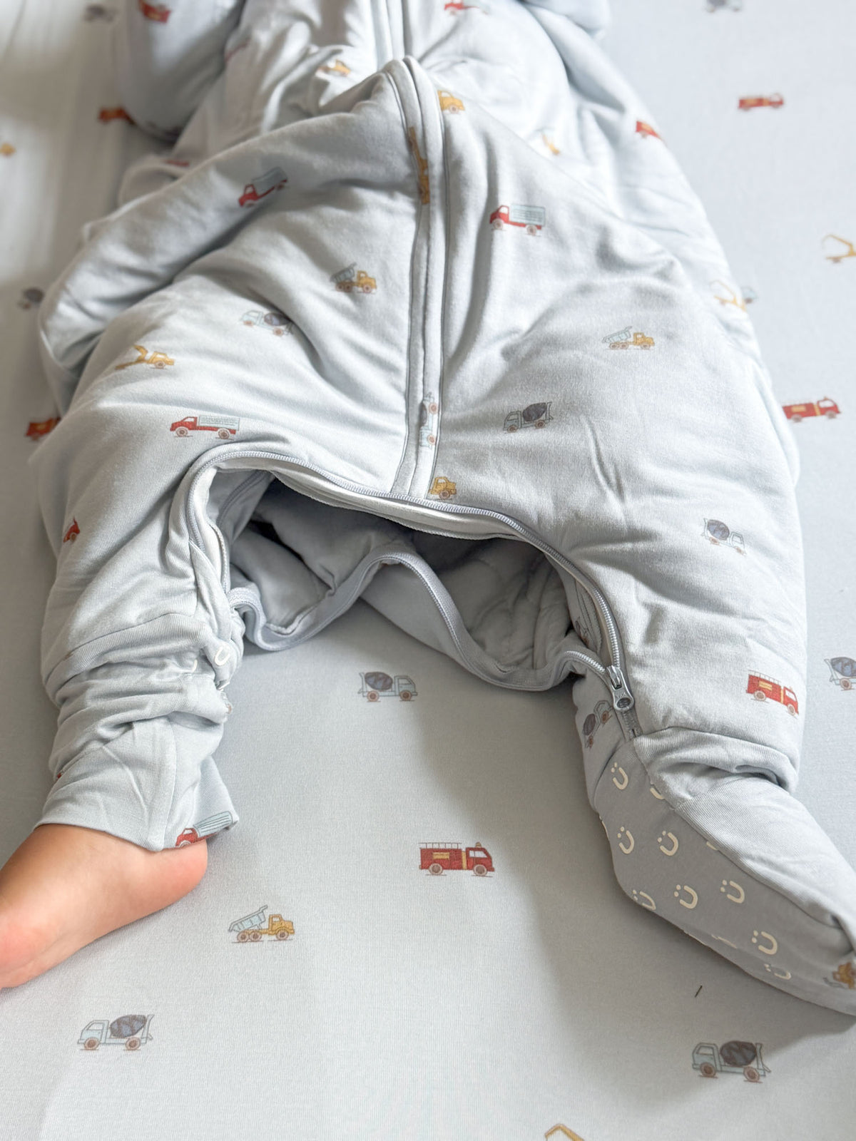 Footed sleep sack with light gray vehicle pattern, zip front, and fold-over hand cuffs