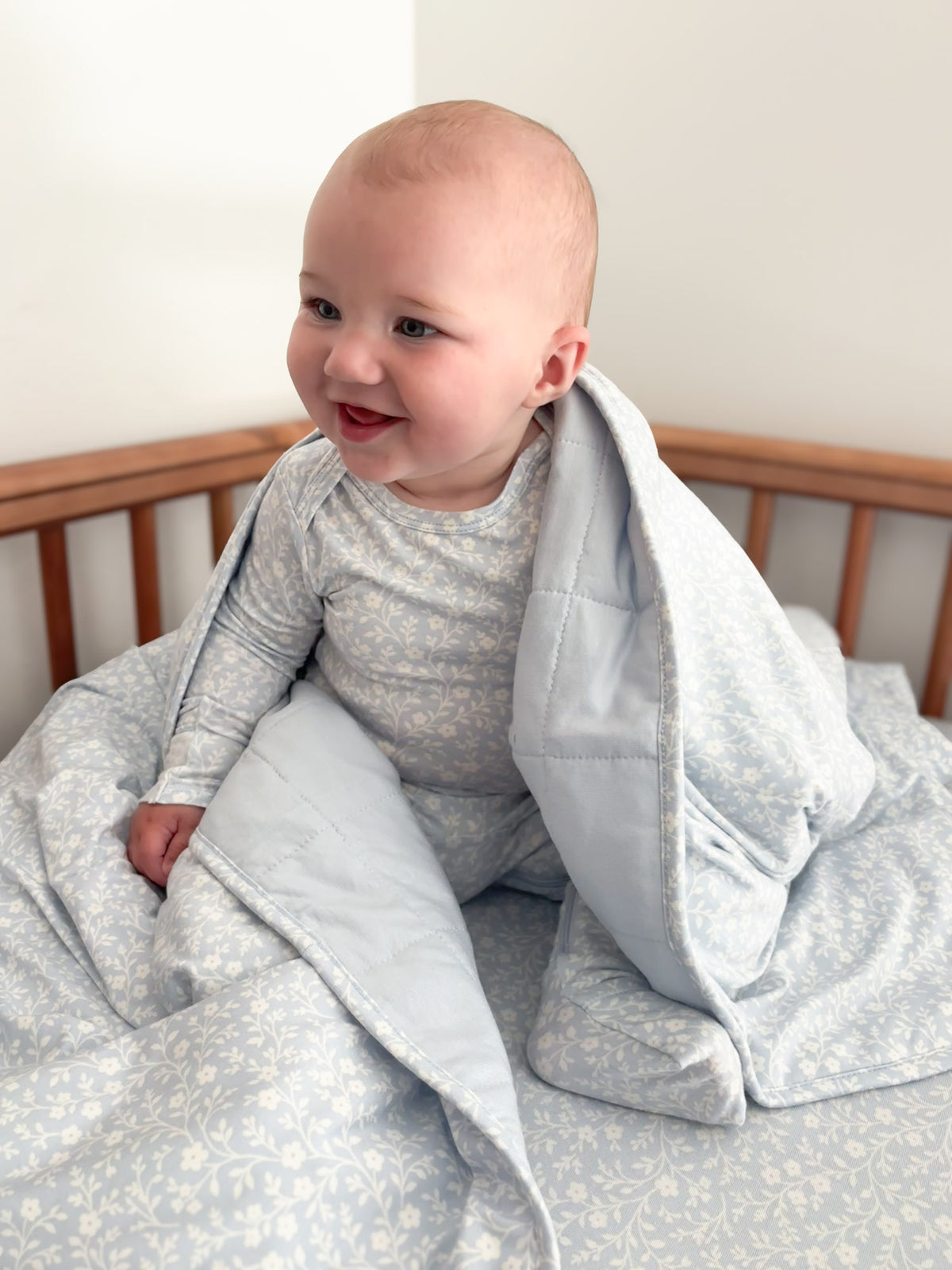 Baby cloud blanket in light blue floral pattern with front hood and draped wrap around infant